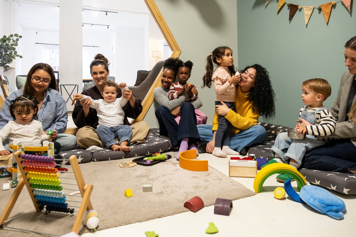 Parents and their young toddlers enjoying playtime on the floor together in a daycare