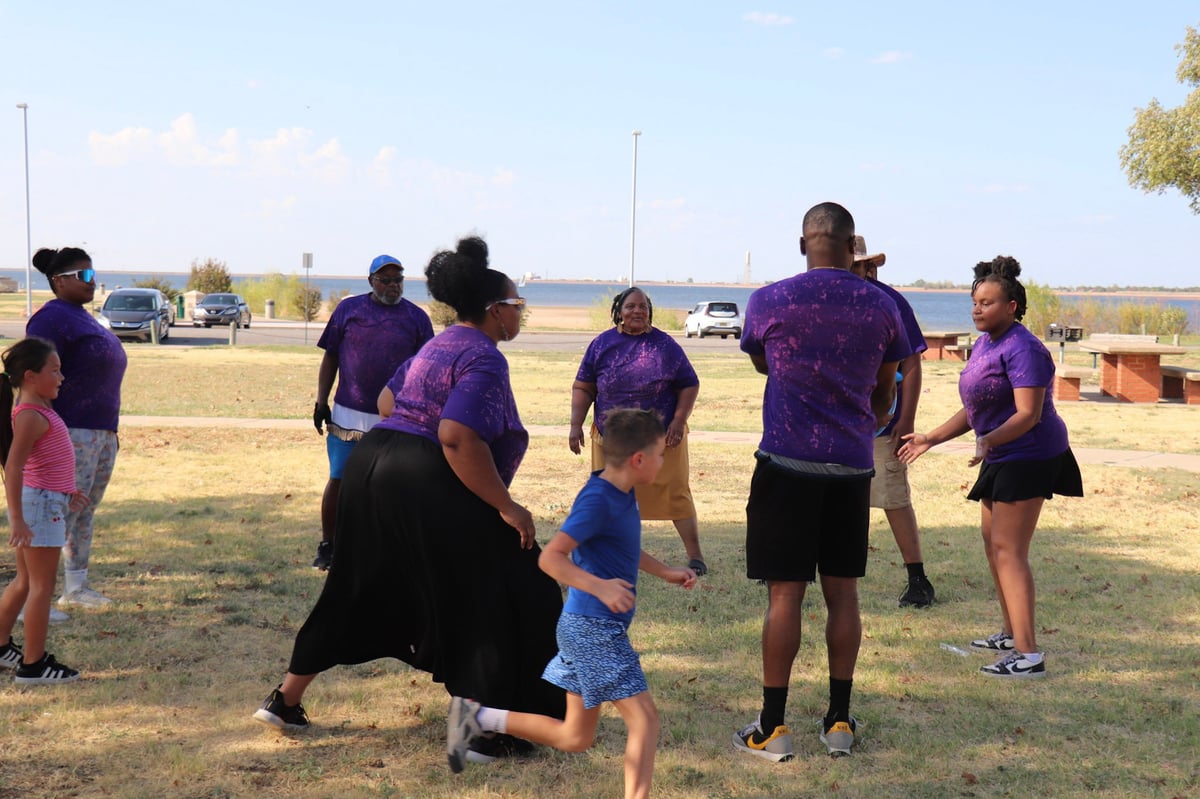 Group of people in purple shirts playing football or tag game in an open field during daytime